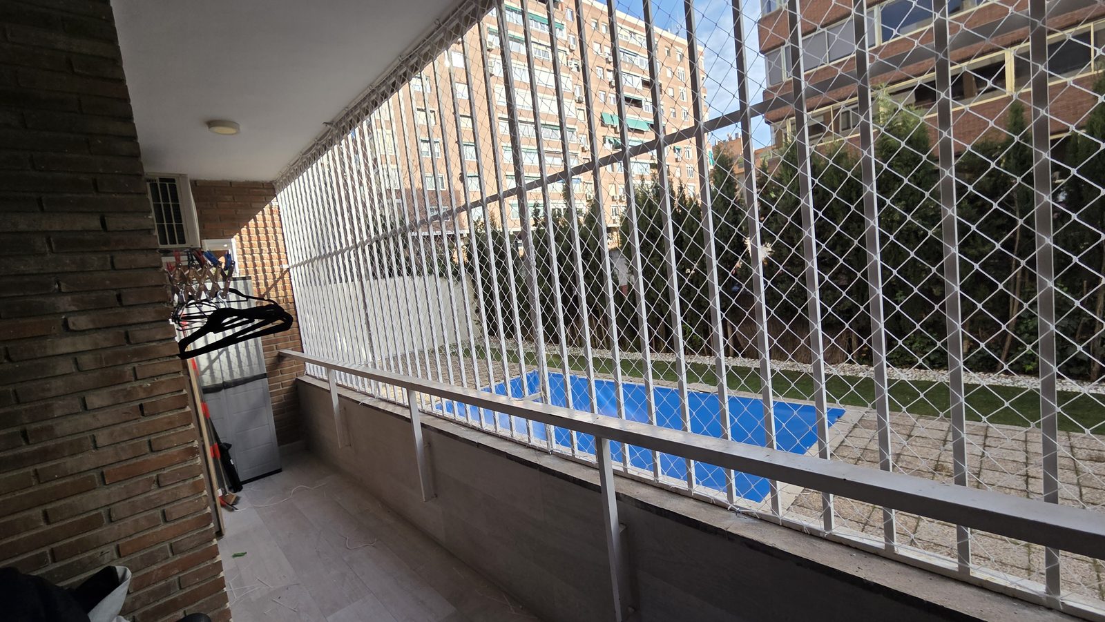 Balcón con red de seguridad junto a una piscina comunitaria