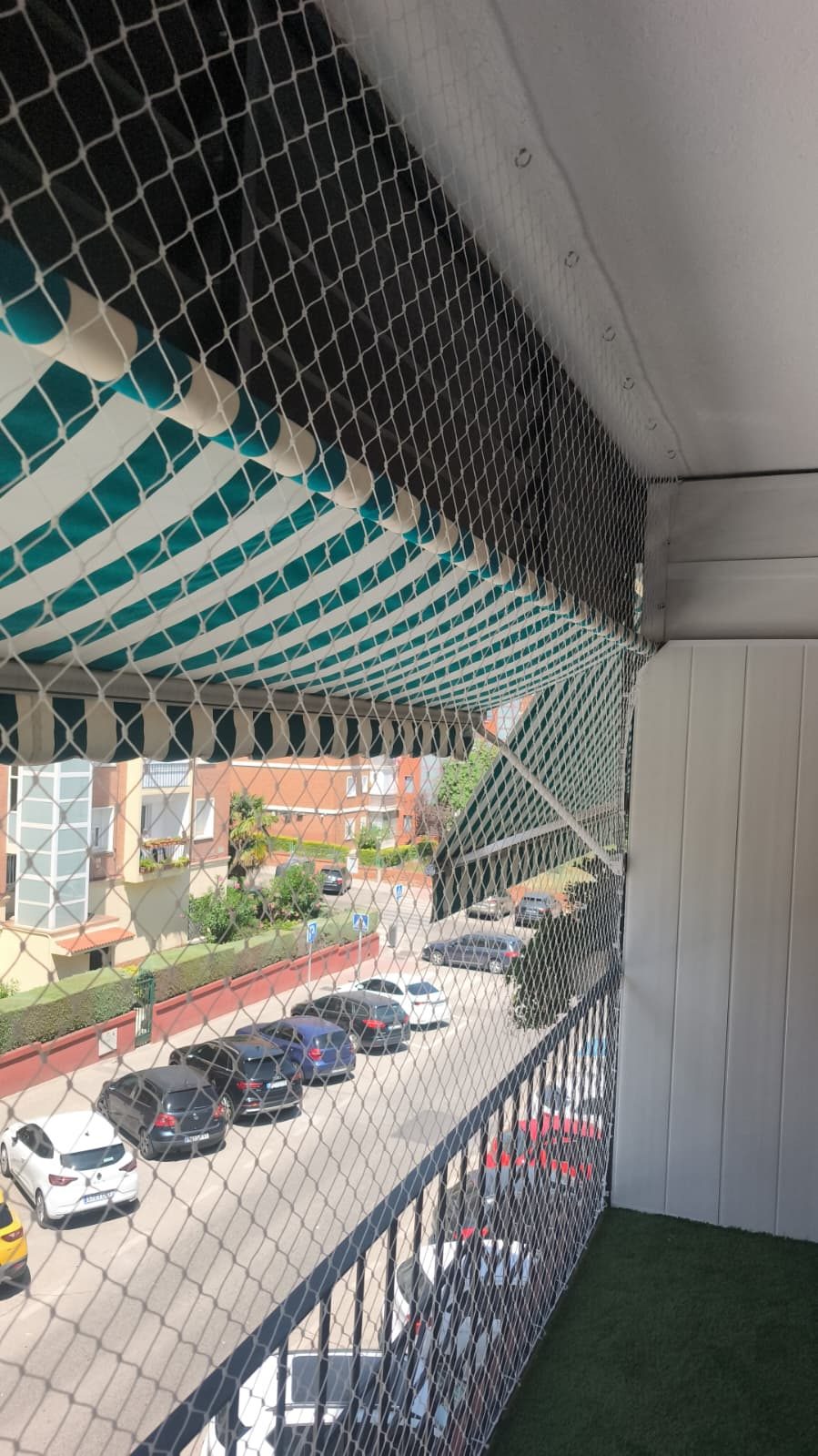 Balcón con toldo y red de protección sobre la calle