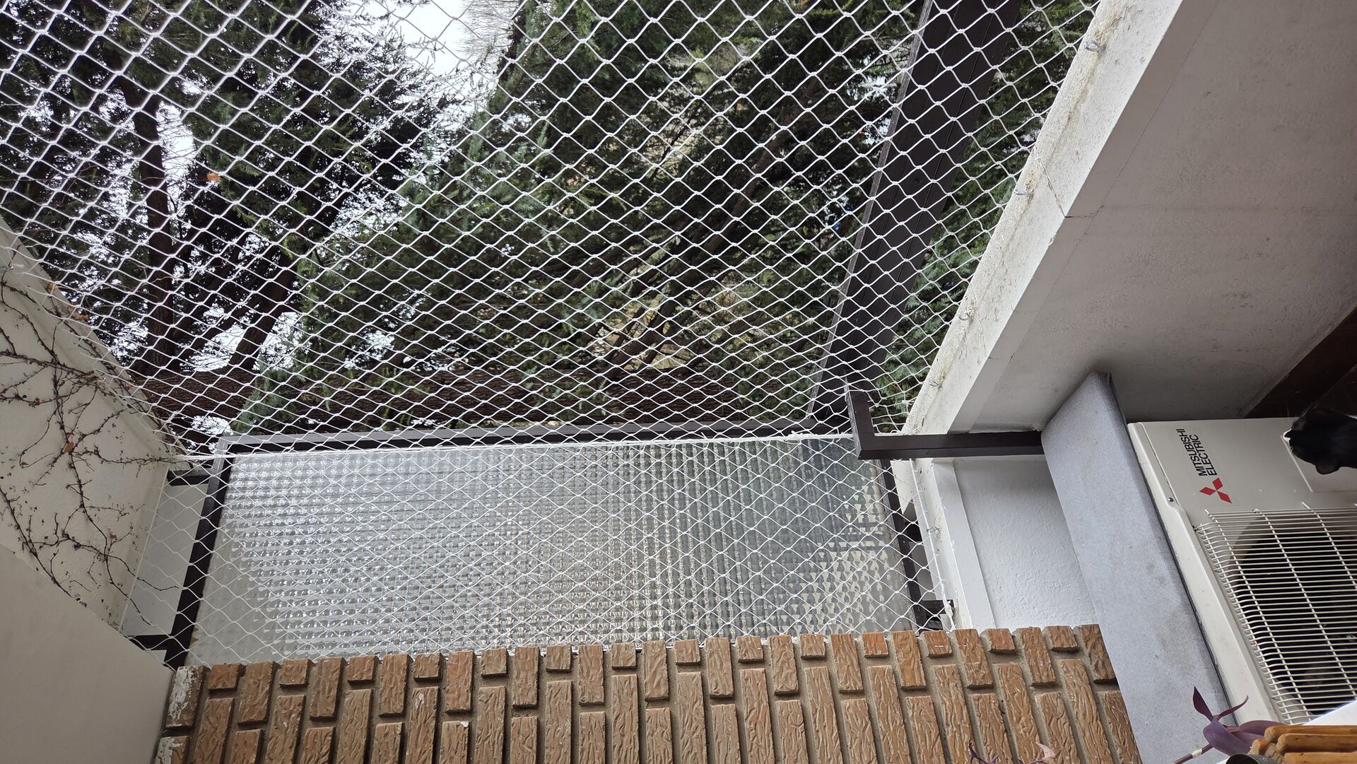 Balcón con red de seguridad sobre el suelo y aire acondicionado